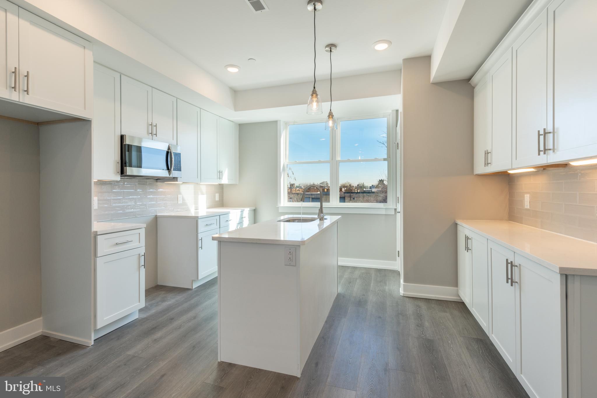 2327 North 3rd Street Philadelphia, PA 19133 - Photo 4 of 28 a kitchen with kitchen island white cabinets and stainless steel appliances
