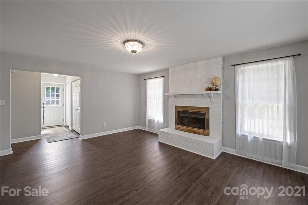 10017 Sardis Oaks Road Charlotte, NC 28270 - Photo 6 of 31 an empty room with wooden floor fireplace and windows