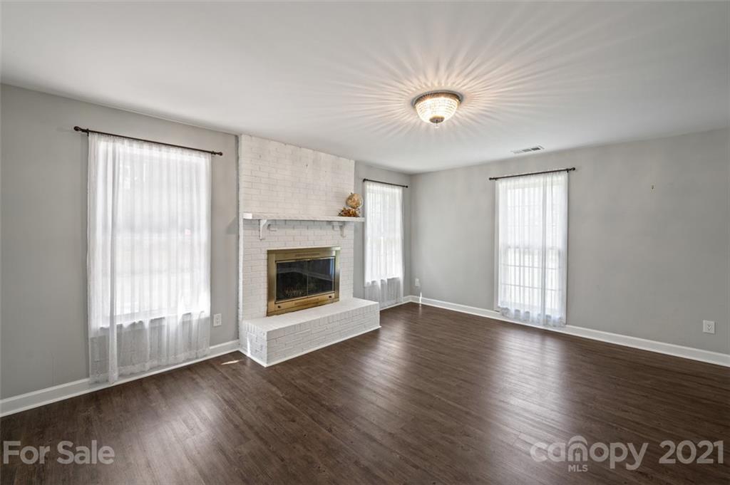 10017 Sardis Oaks Road Charlotte, NC 28270 - Photo 7 of 31 an empty room with wooden floor a ceiling fan and windows