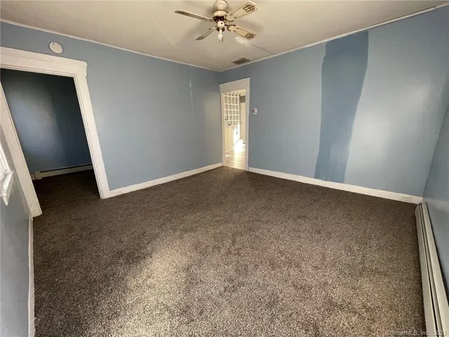 an empty room with a ceiling fan and carpet