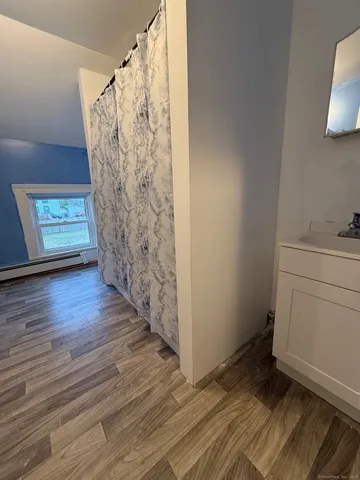 a view of an empty room with a window and wooden floor