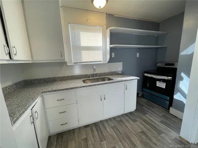 a kitchen with granite countertop white cabinets and a stove