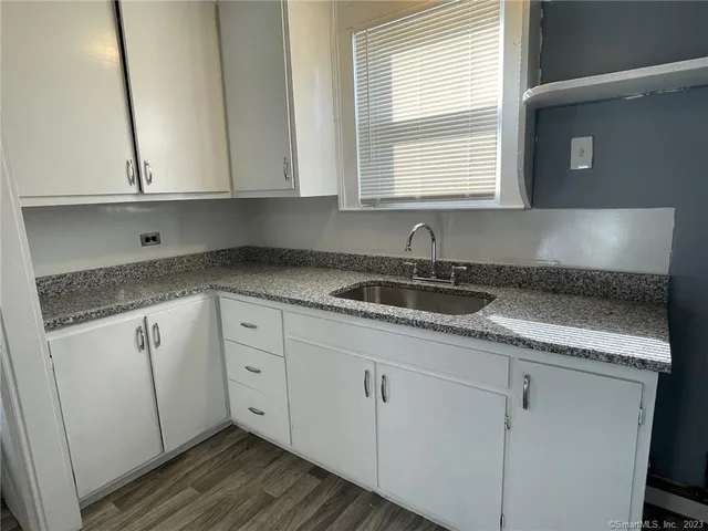 a kitchen with granite countertop white cabinets and sink