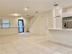 a view of empty room with kitchen and window