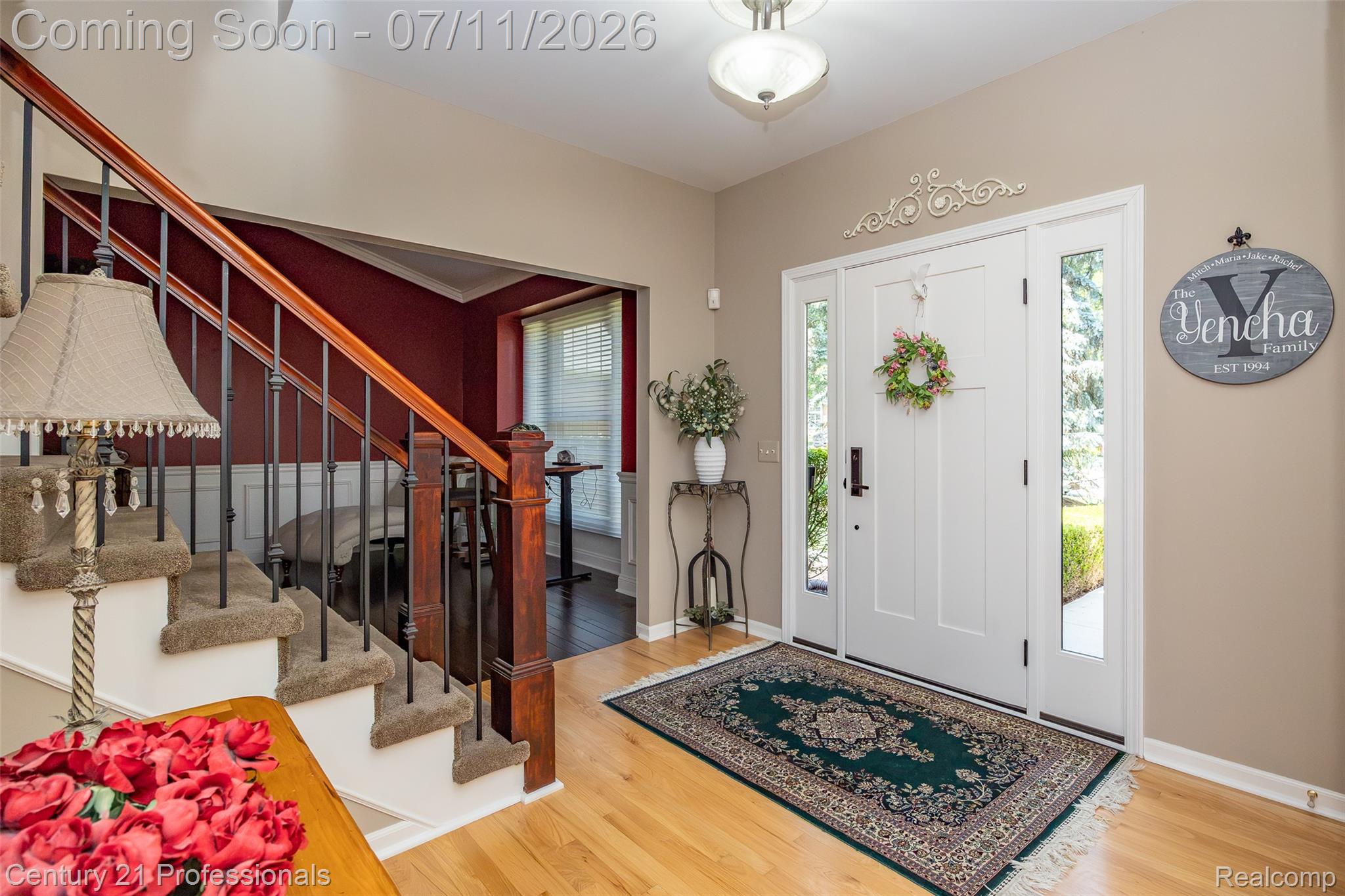 689 Woodfield Way Rochester, MI 48307 - Photo 34 of 61 Foyer with a white entry door featuring clear glass sidelights, light wood-finish flooring, and a staircase with dark wood-finish handrails and black metal balusters
