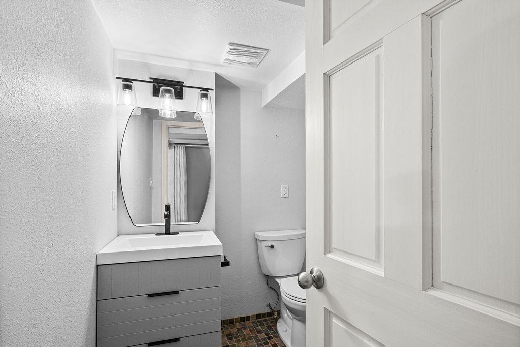 5007 Colorado Street Duluth, MN 55804 - Photo 21 of 31 Bathroom featuring vanity, a textured ceiling, a textured wall, and dark tile patterned floors