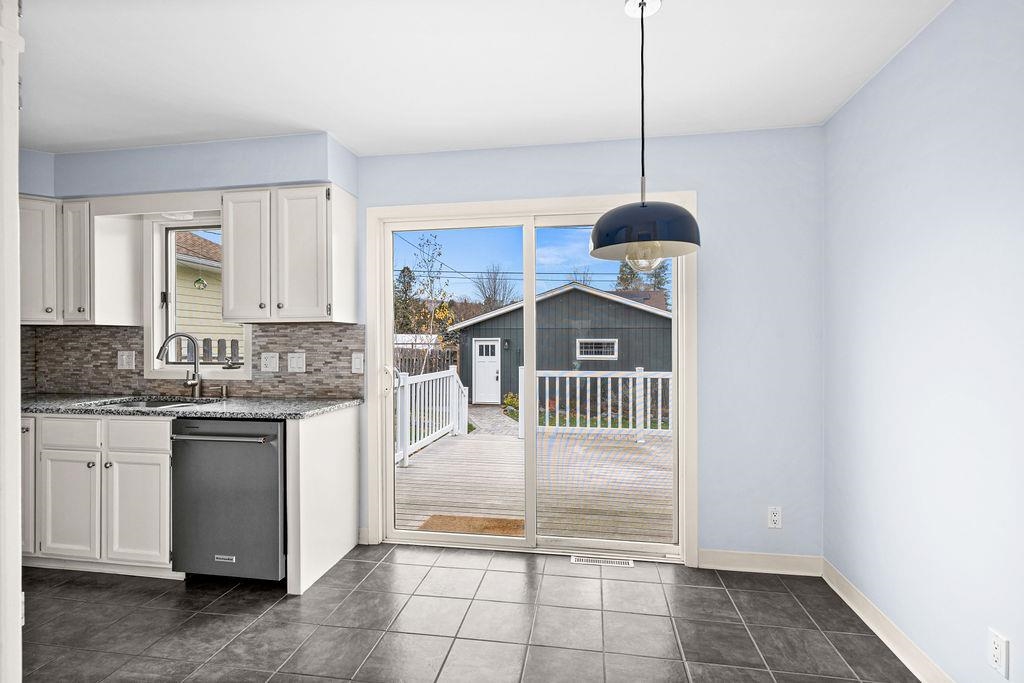 5007 Colorado Street Duluth, MN 55804 - Photo 3 of 31 Kitchen featuring white cabinetry, stainless steel dishwasher, dark stone countertops, and dark tile patterned floors