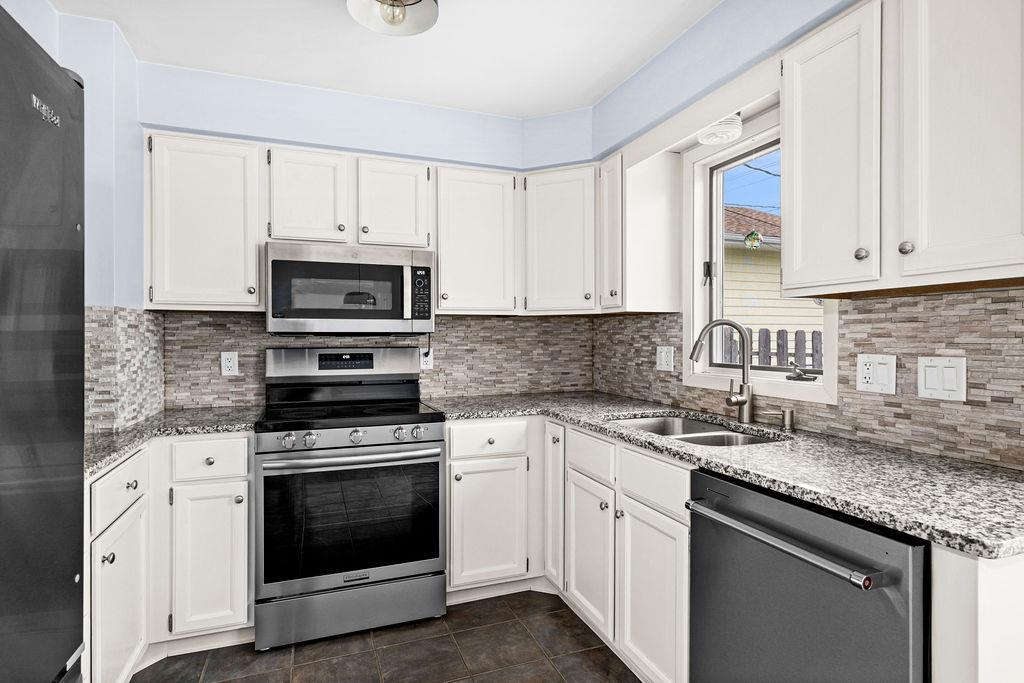 5007 Colorado Street Duluth, MN 55804 - Photo 5 of 31 Kitchen featuring appliances with stainless steel finishes, decorative backsplash, white cabinetry, and light stone countertops
