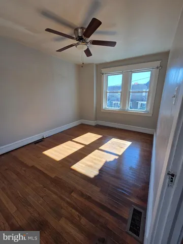 a view of an empty room with window and wooden floor
