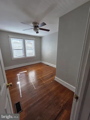 an empty room with wooden floor ceiling fan and windows