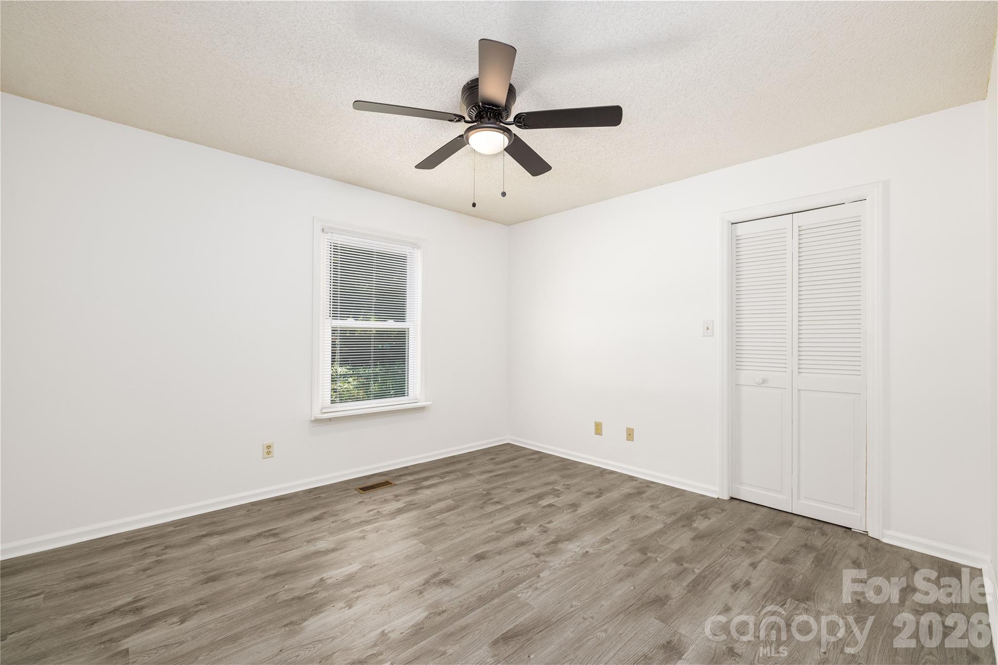21014 Pine Ridge Drive Cornelius, NC 28031 - Photo 18 of 26 an empty room with wooden floor ceiling fan and windows