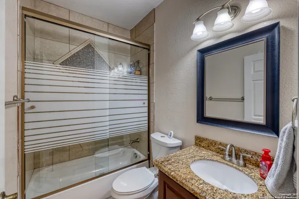 a bathroom with a granite countertop sink toilet a mirror and shower