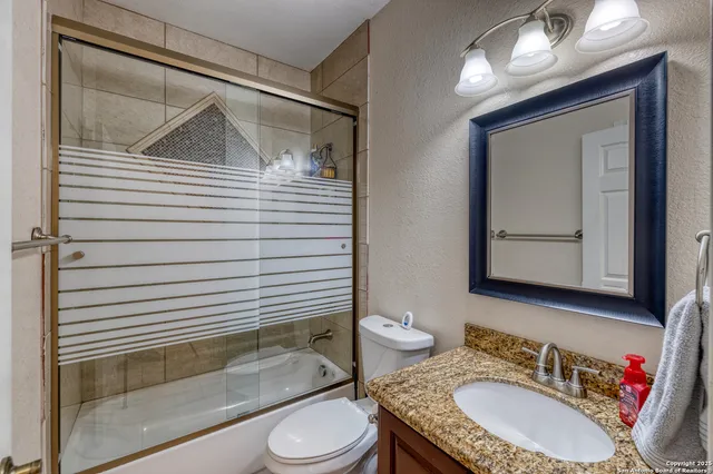 a bathroom with a granite countertop sink toilet a mirror and shower