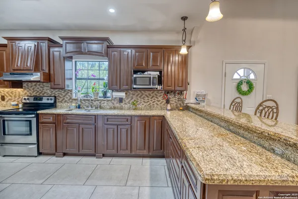 a large kitchen with granite countertop a sink and stove