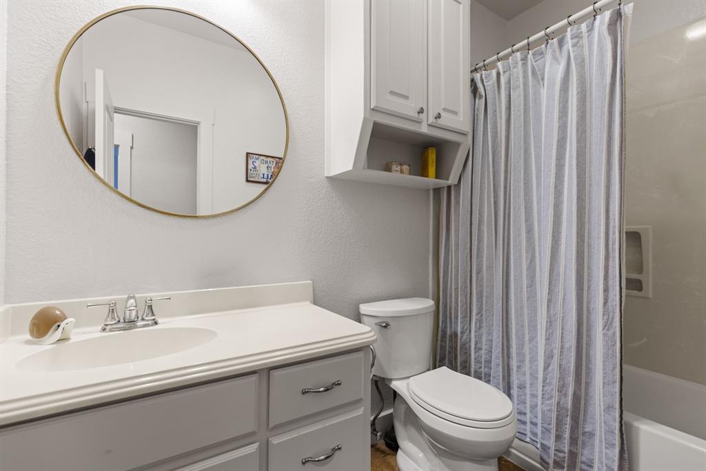 10609 Aquilla Trail Waco, TX 76708 - Photo 29 of 30 Bathroom vanity featuring an integrated sink, polished chrome faucet, and a large circular mirror