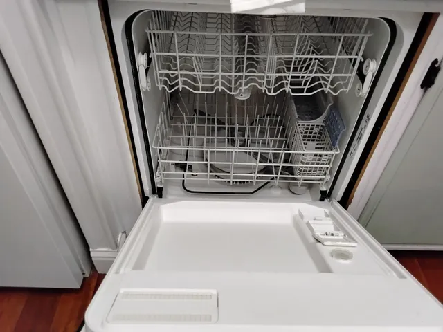 a kitchen with stainless steel appliances a stove top oven a sink a refrigerator white cabinets and wooden floor