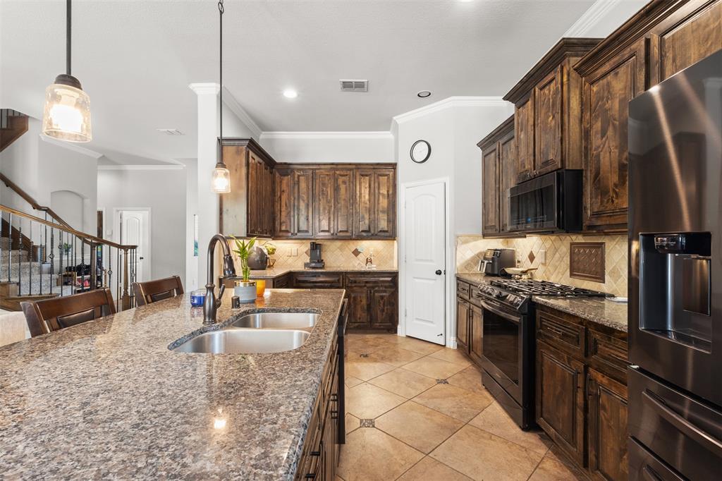 800 Goose Court Forney, TX 75126 - Photo 14 of 34 a large kitchen with stainless steel appliances granite countertop a stove a sink dishwasher a dining table and chairs with wooden floor