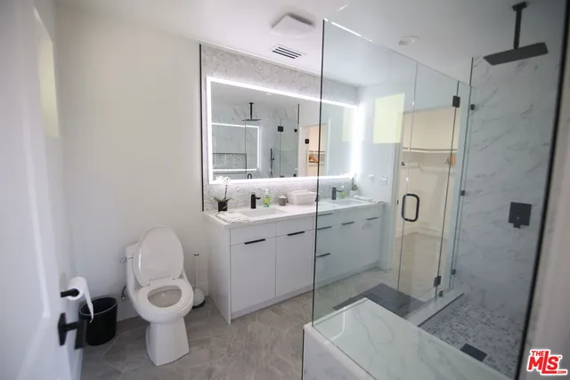 a bathroom with a granite countertop sink toilet and shower