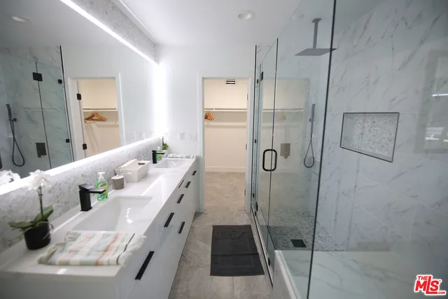 a bathroom with a double vanity sink a large mirror and shower