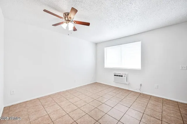 an empty room with windows and fan