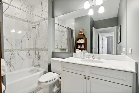 a bathroom with a bathtub shower sink vanity mirror and toilet