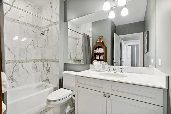 a bathroom with a bathtub shower sink vanity mirror and toilet