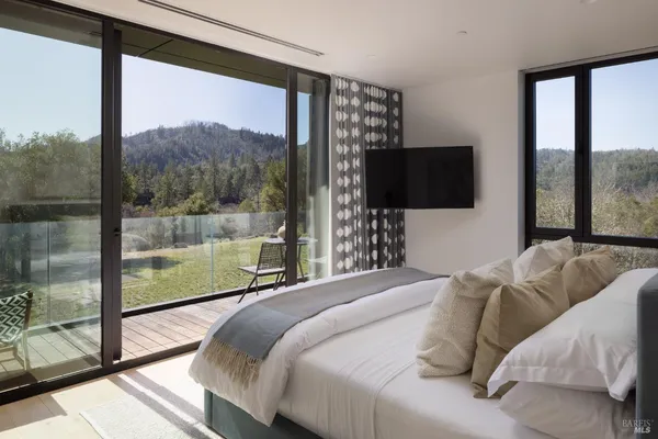a bedroom with a bed and a flat tv screen next to a window