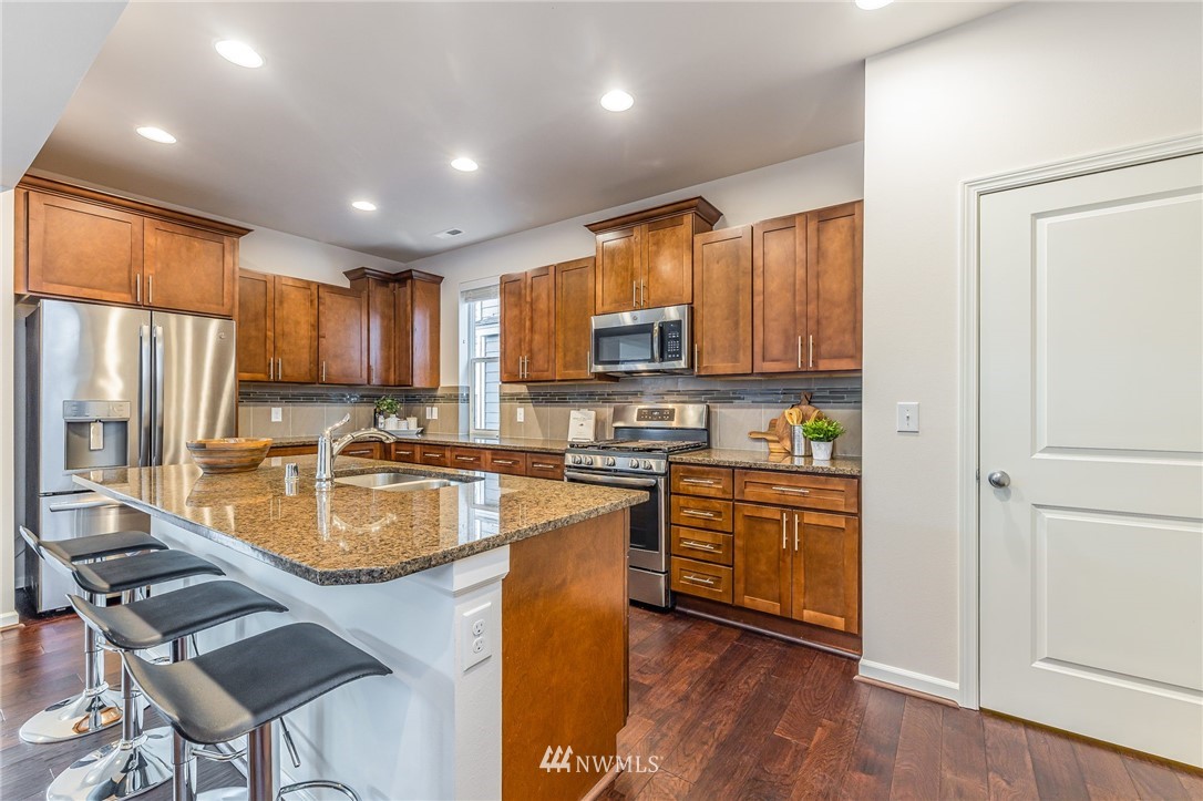 4303 Riverfront Boulevard Everett, WA 98203 - Photo 13 of 40 a kitchen with stainless steel appliances granite countertop a refrigerator a stove top oven a sink dishwasher and wooden cabinets with wooden floor