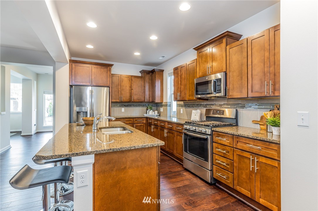 4303 Riverfront Boulevard Everett, WA 98203 - Photo 15 of 40 a large kitchen with kitchen island granite countertop wooden cabinets a stove a sink a dining table and chairs