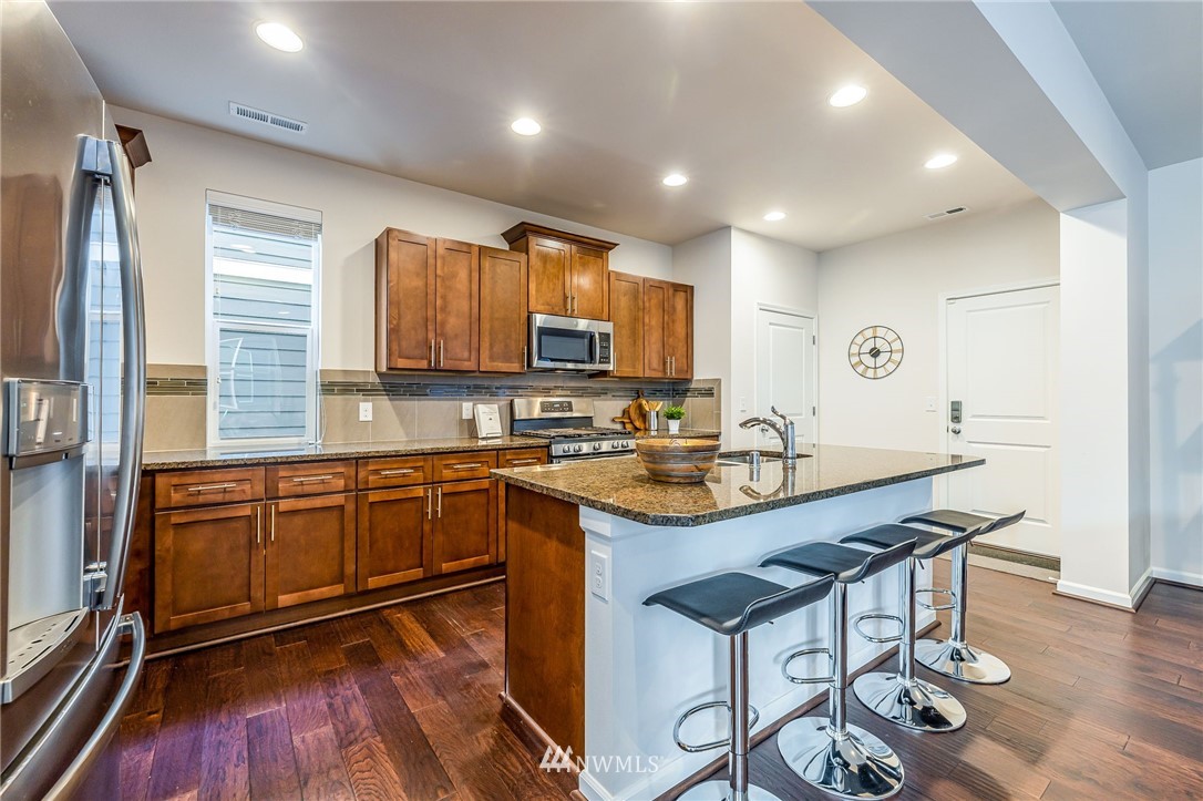 4303 Riverfront Boulevard Everett, WA 98203 - Photo 10 of 40 a kitchen with stainless steel appliances granite countertop wooden cabinets a sink a stove a dining table and chairs