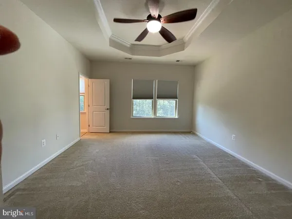 an empty room with chandelier fan and windows