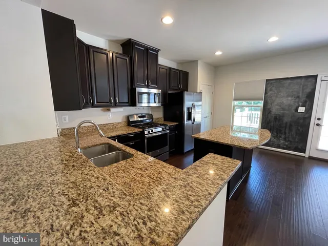 a kitchen with granite countertop wooden cabinets a refrigerator and a sink