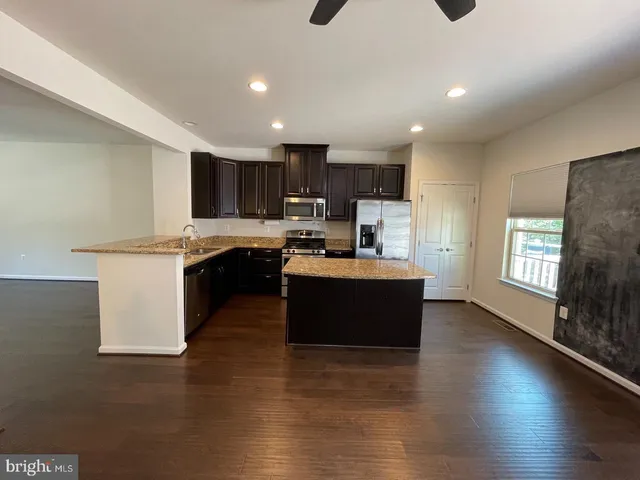 a large kitchen with stainless steel appliances granite countertop a stove a sink a refrigerator and a microwave