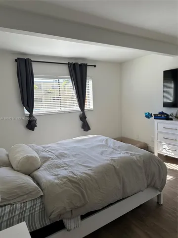 a bedroom with a bed a flat screen tv and window