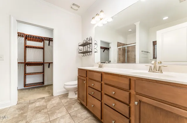 a spacious bathroom with a double vanity sink a toilet and a mirror