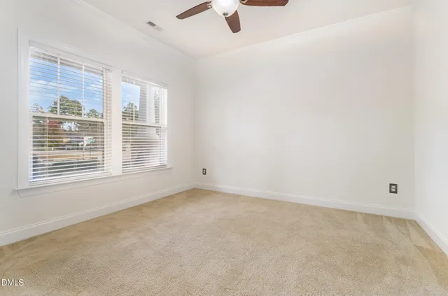 an empty room with ceiling fan and window