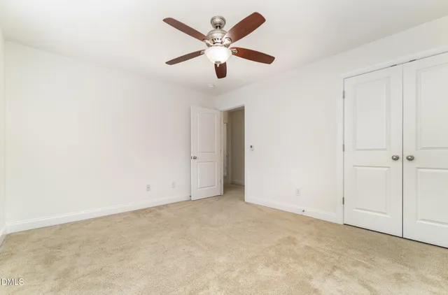 an empty room with closet and a ceiling fan