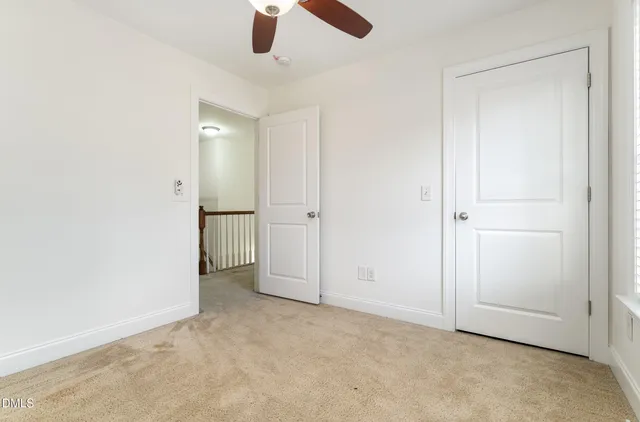 an empty room with ceiling fan and window