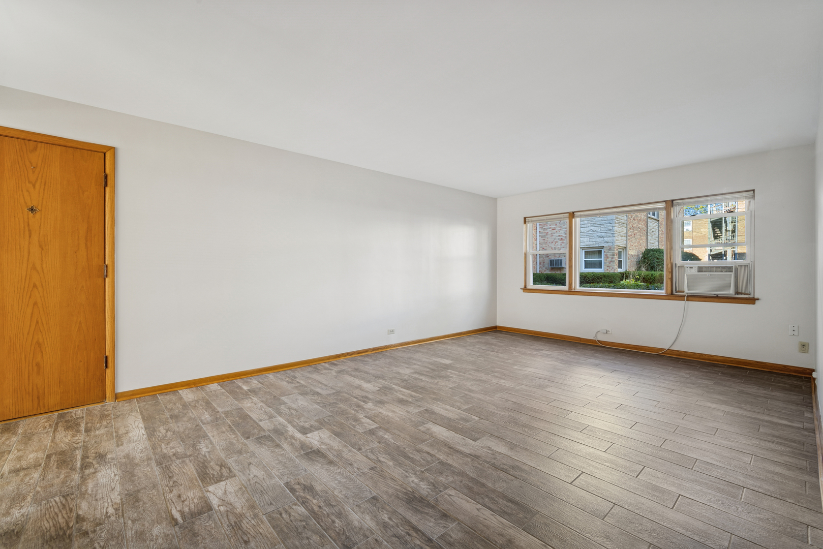 6800 North Overhill Avenue, Unit 1A Chicago, IL 60631 - Photo 2 of 20 a view of an empty room with a window and wooden floor