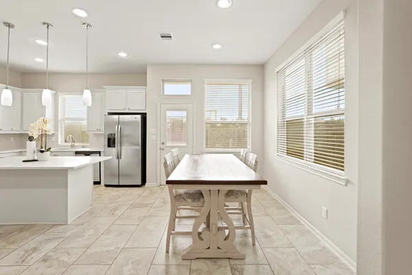 a kitchen with stainless steel appliances kitchen island granite countertop a refrigerator a sink a stove and white cabinets with wooden floor