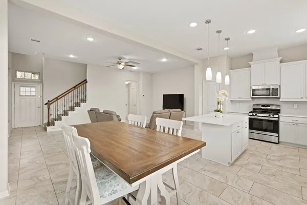 a kitchen with stainless steel appliances kitchen island granite countertop a stove a sink a dining table and chairs
