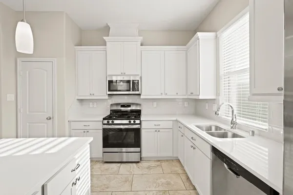 a kitchen with white cabinets and appliances