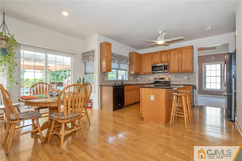 15 Crescent Road Old Bridge, NJ 08857 - Photo 5 of 19 a kitchen with stainless steel appliances kitchen island granite countertop a stove top oven a sink a dining table and chairs with wooden floor