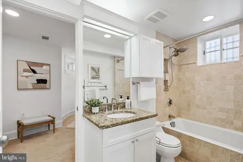 a bathroom with a granite countertop sink mirror toilet and bathtub