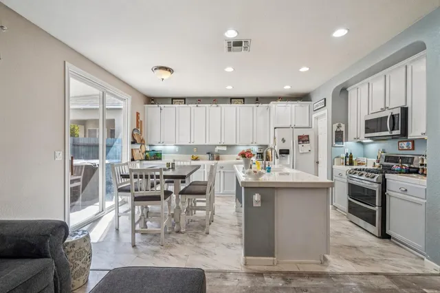 a kitchen with stainless steel appliances granite countertop a stove top oven a sink a dining table and chairs