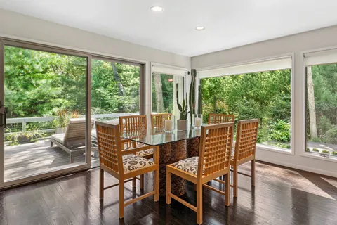 a view of a city from a dining room with large windows and wooden floor