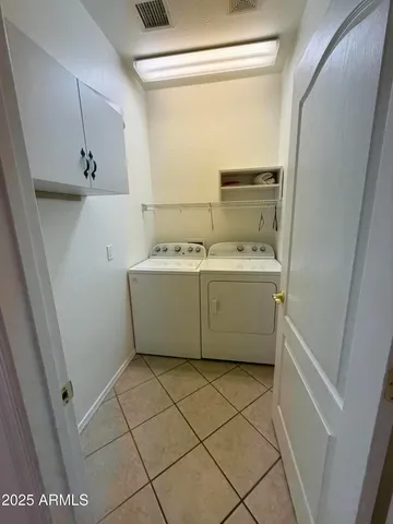 a utility room with a washer dryer and white cabinets