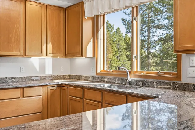 a kitchen with stainless steel appliances granite countertop a sink and a large window