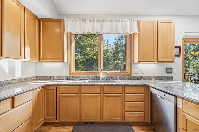 a kitchen with granite countertop wooden cabinets a sink and a window
