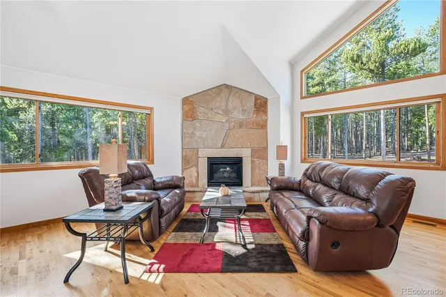 a living room with furniture a fireplace and large windows